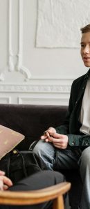 Man in Black Suit Jacket Sitting on Brown Wooden Armchair